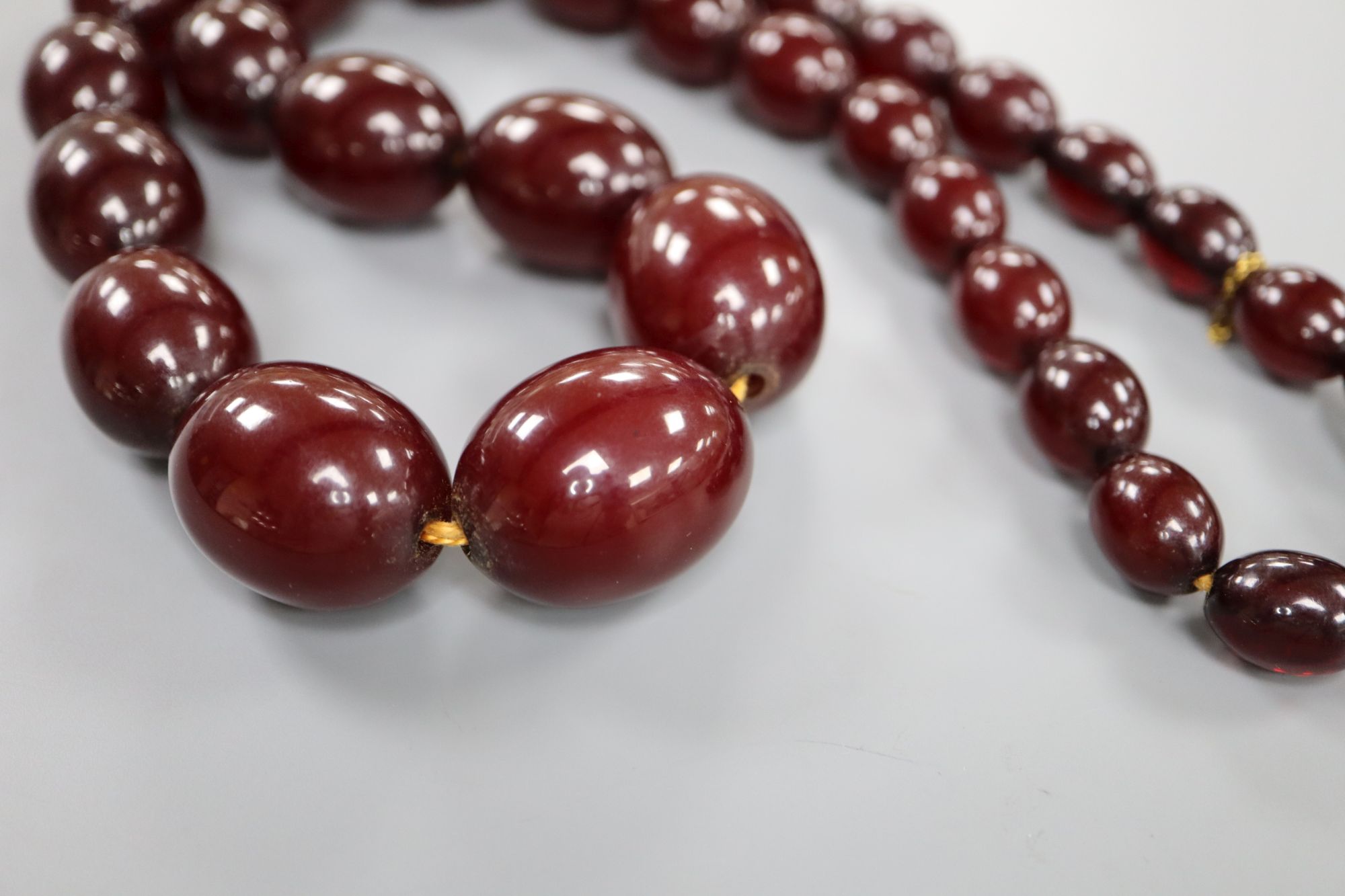 A single strand graduated simulated cherry amber oval bead necklace, 61cm, gross weight 99 grams.